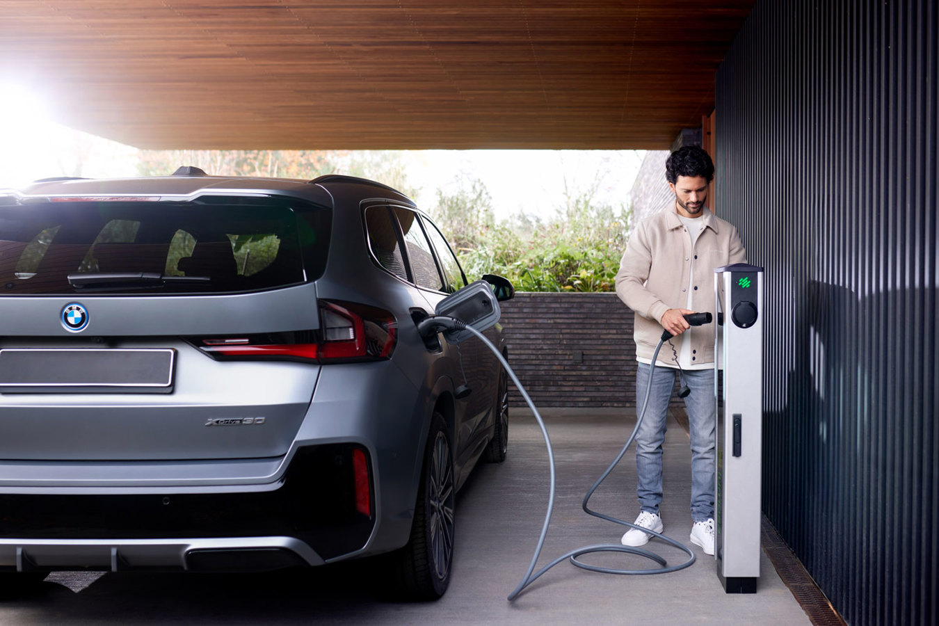 Man standing next to Lumosa TRACK AC EV charger near an office building